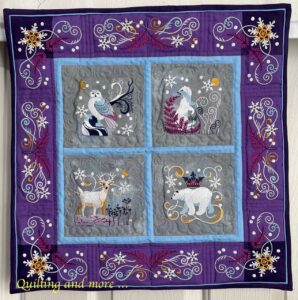 Small embroidered quilt with four animal blocks and embroidered borders.