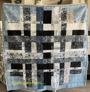 Blue, black and grey quilt done in squares and rectangles.