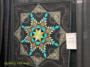 Teal and gold star quilt on black background.