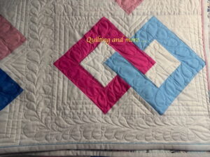 Detail of quilting, showing ruler work in the setting triangles around the hollow squares; there are hearts inside the squares.