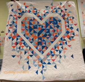 Blue and orange quilt on white background, with the colors "missing" in areas to form a large heart of the background fabric.