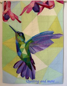Hummingbird in greens, blues & purples flies toward pink/purple flowers against a pale green background.